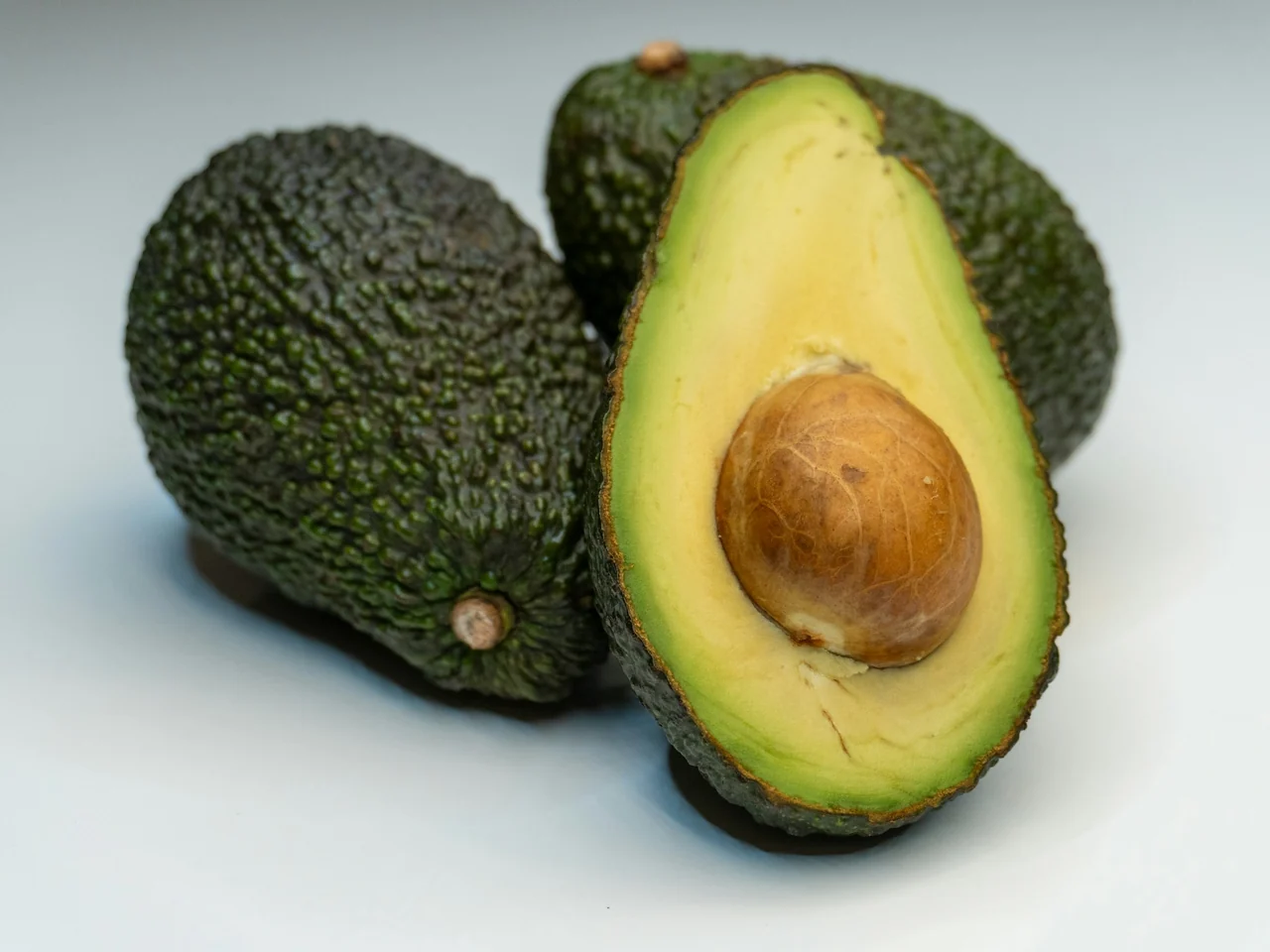 Two avocados, one halved to show the stone